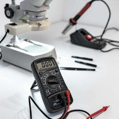 Electronics workbench with multimeter, microscope, and soldering iron.